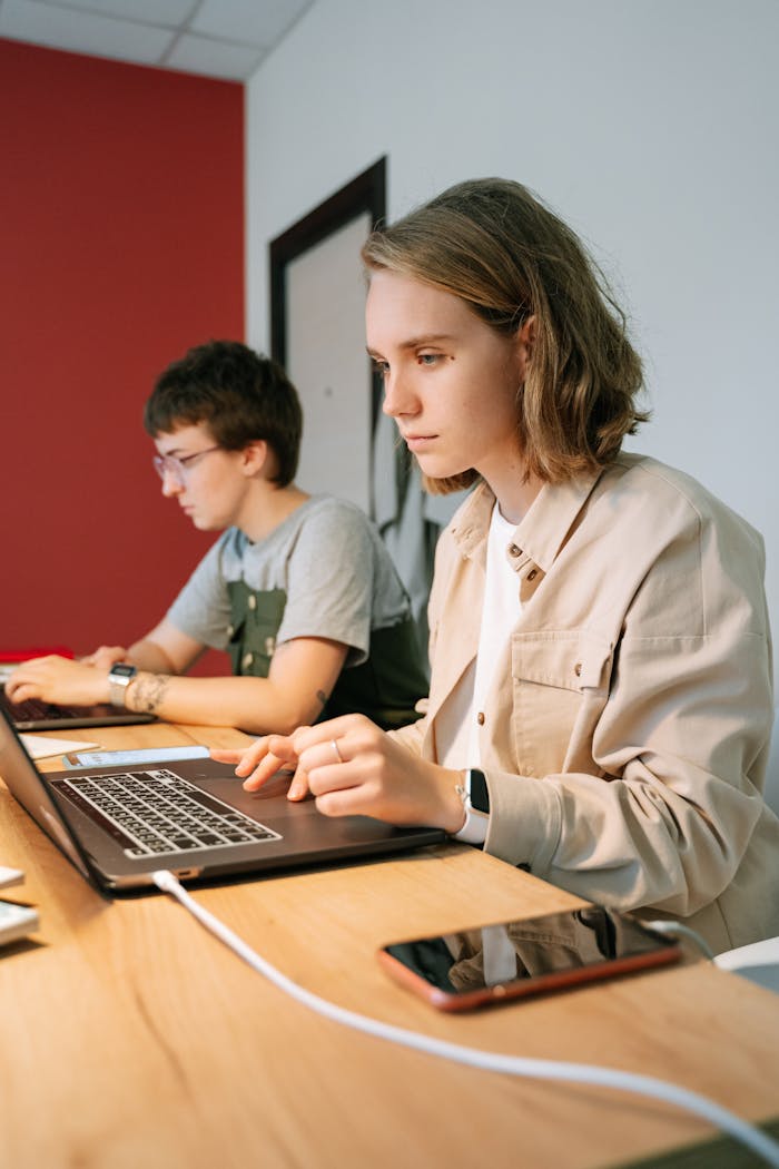 Two young professionals focused on work at a shared workspace, collaborating efficiently.